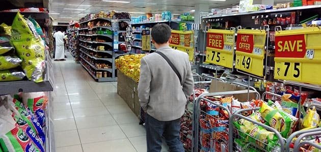 مشتري ينظر إلى رفوف في محل تجاري، عليه أسعار اقل من 0.99$