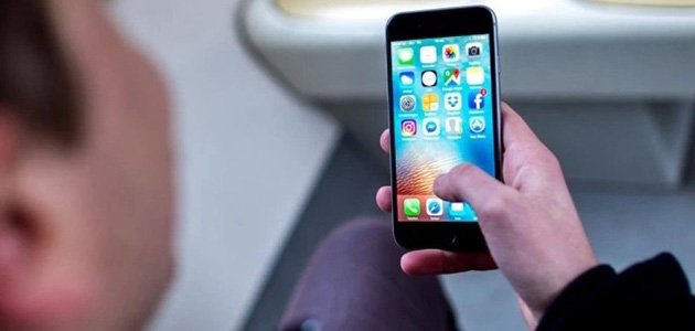 رجل يمسك بهاتف أيفون في يده ويقوم بحذف التطبيقات الضارة
