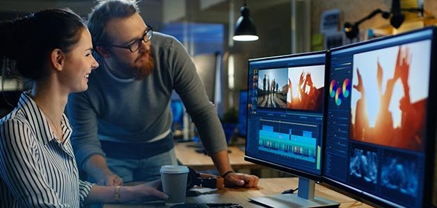مصمم جرافيكس يستخدم برنامج تعديل فيديو على شاشة حاسوب
