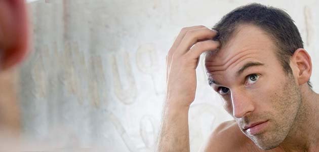 شاب ينظر الى شعره المتساقط