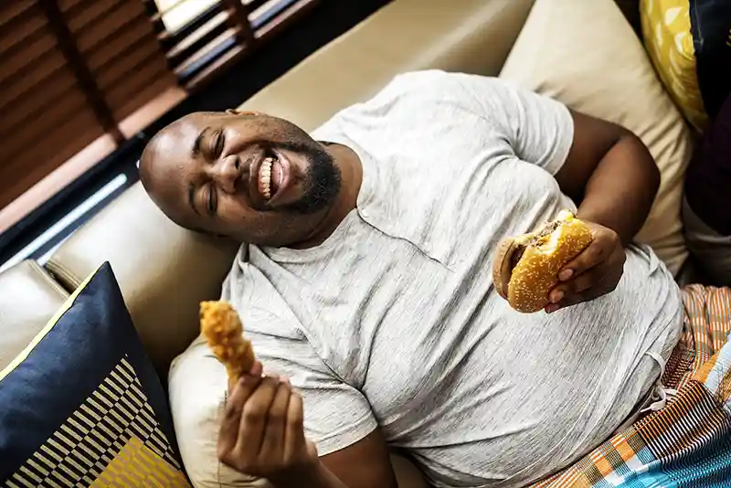 رجل يأكل Fast Food مليء بالدهون